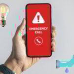 Hand holding phone showing emergency call alert, symbolizing urgent landlord repairs.