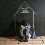 Person sitting on floor under chalk outline of a house labeled “Section 21 Eviction,” symbolizing housing insecurity