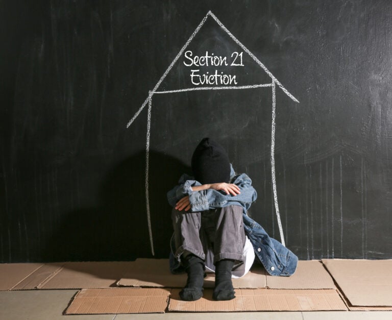 Person sitting on floor under chalk outline of a house labeled “Section 21 Eviction,” symbolizing housing insecurity