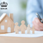 Wooden figures of a family beside a house model representing UK government housing plans
