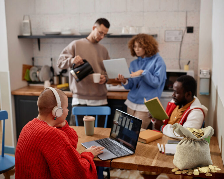 Group of young professionals collaborating in a shared workspace with laptops and coffee