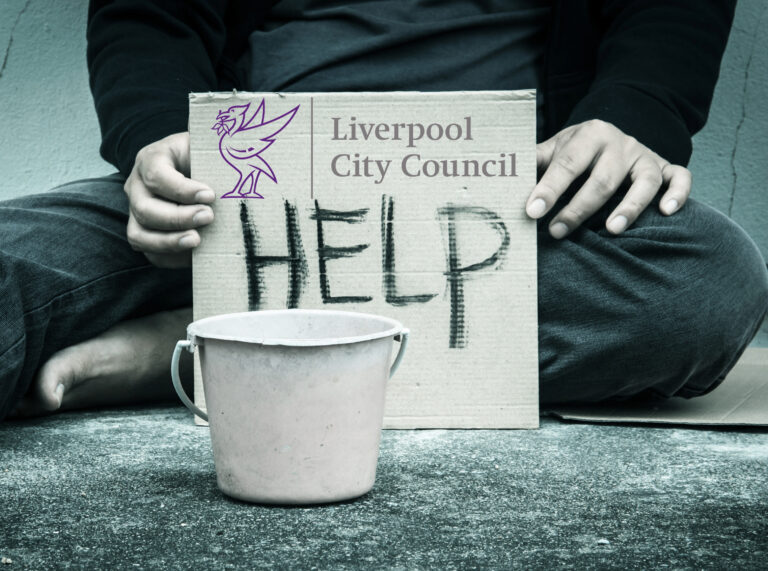 Cardboard sign reading “HELP” with Liverpool City Council logo, symbolising homelessness support efforts.