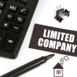 Calculater and pen with a drawing of a house and a limited company label