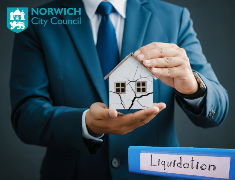 Businessperson holding a cracked house model symbolizing Norwich City Council housing company liquidation