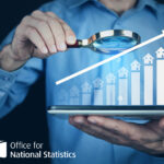 Bar chart with houses on the up with a man looking at it with a magnifying glass