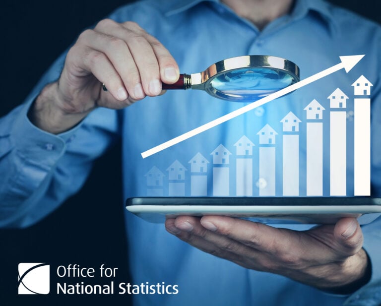 Bar chart with houses on the up with a man looking at it with a magnifying glass
