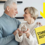 Middle aged couple holing a house next to a stamp duty notepad and down arrow
