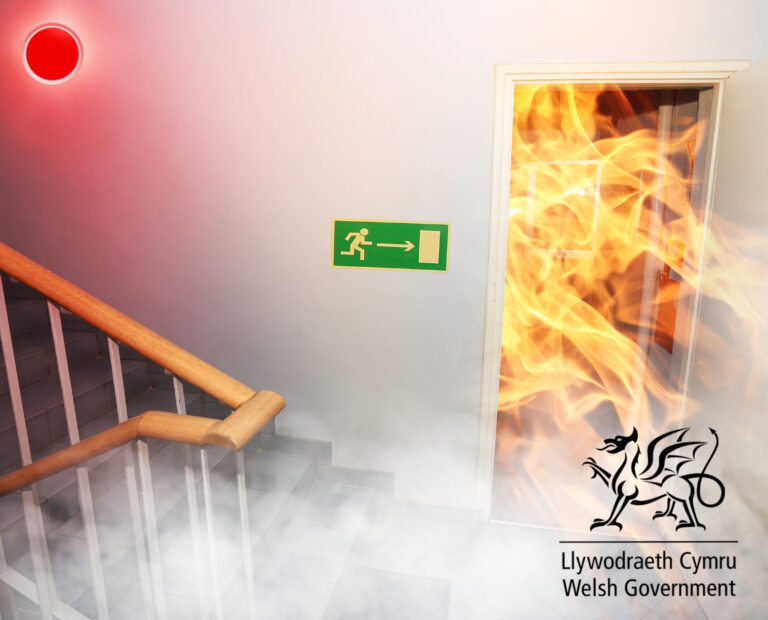Fire and alarm with stairs in a hallway with the welsh government logo