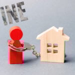 Symbol of landlord fines with figure in handcuffs chained to a house