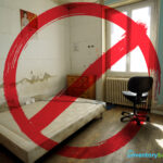 Unfit rental property with damp walls and broken furniture marked with a red prohibition sign