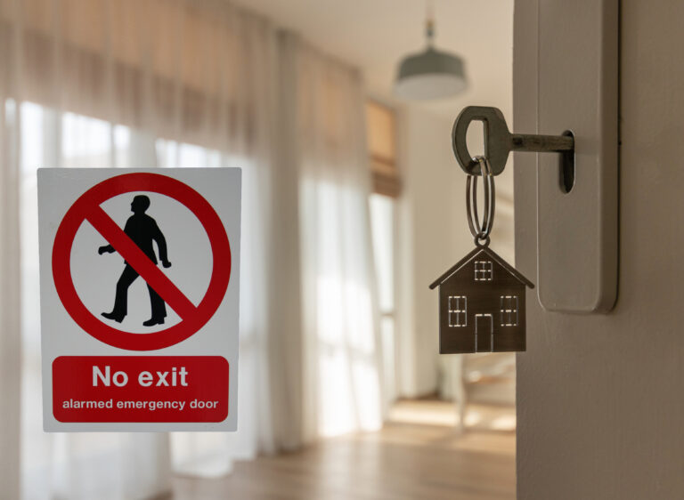 House key in door beside a “No exit” sign, symbolising stability in the rental market