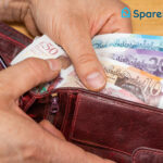 Person holding a wallet filled with British banknotes, illustrating rising rent costs.
