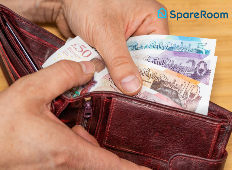 Person holding a wallet filled with British banknotes, illustrating rising rent costs.