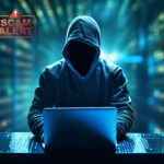 Hooded scammer at laptop with “Scam Alert” warning symbol.