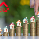 Miniature houses on stacked coins symbolising rising housing costs and social housing investment.