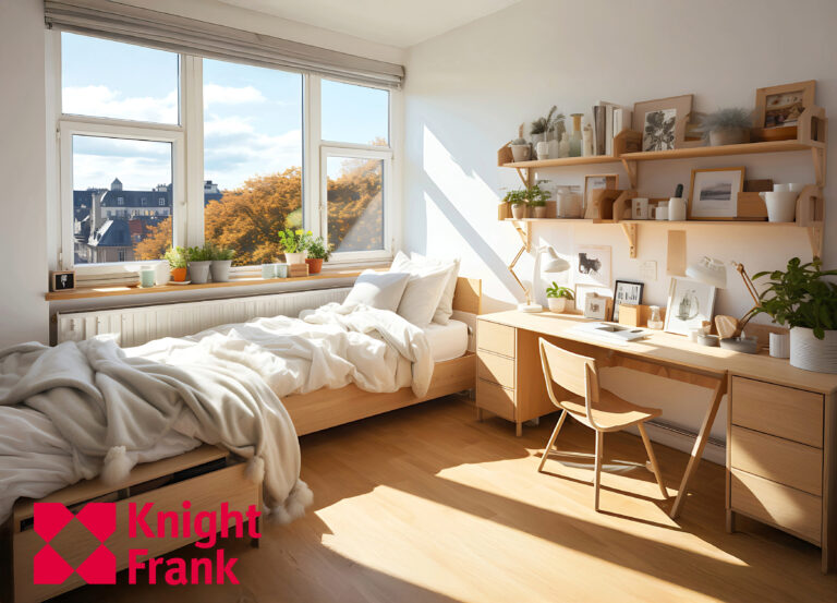 Modern student bedroom with desk, shelving, and large window overlooking city rooftops.