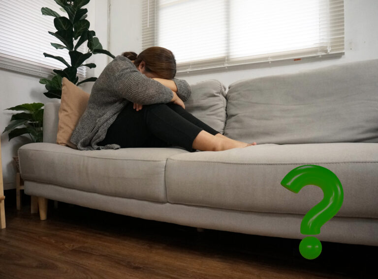 Woman sitting on sofa with head down, symbolizing stress and uncertainty about housing safety.