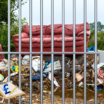 Fly-tipped sofa and rubbish symbolising fines and prison risks for landlords.
