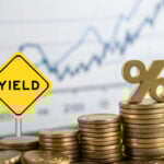 Stacks of coins with yield sign and percentage symbol representing rental yield growth.