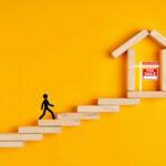 Person climbing steps toward a house with a for sale sign, symbolizing first-time buyers entering the housing market