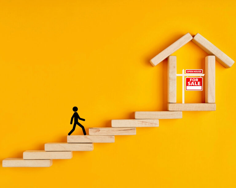 Person climbing steps toward a house with a for sale sign, symbolizing first-time buyers entering the housing market