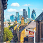 London houses with sold sign and city skyscrapers in background