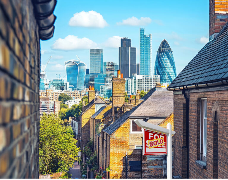 London houses with sold sign and city skyscrapers in background