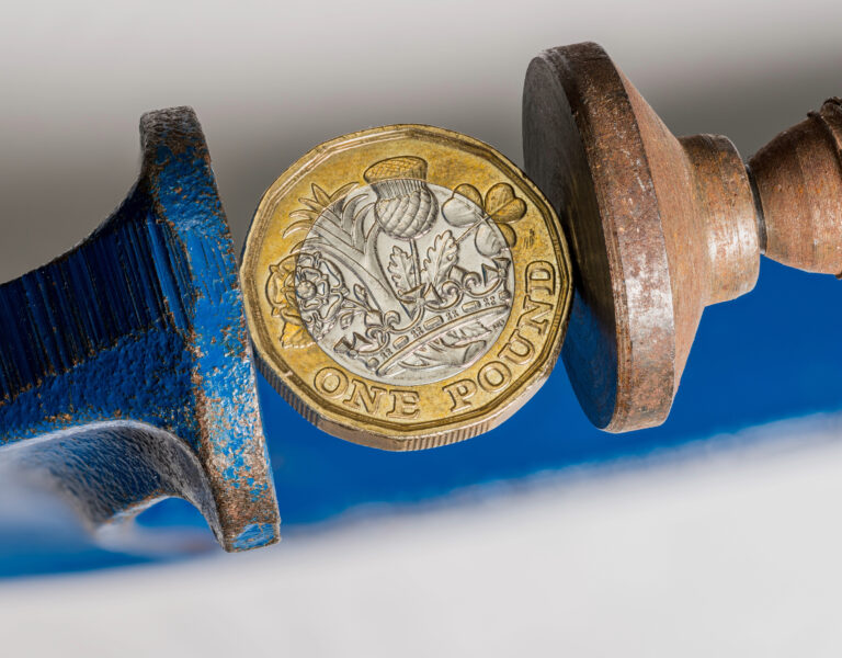 Pound coin squeezed in a clamp symbolising financial pressure on landlords