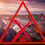 Suburban UK housing with red warning symbol highlighting rental crisis