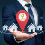 Property investment concept with pound symbol and houses in businessman’s hand