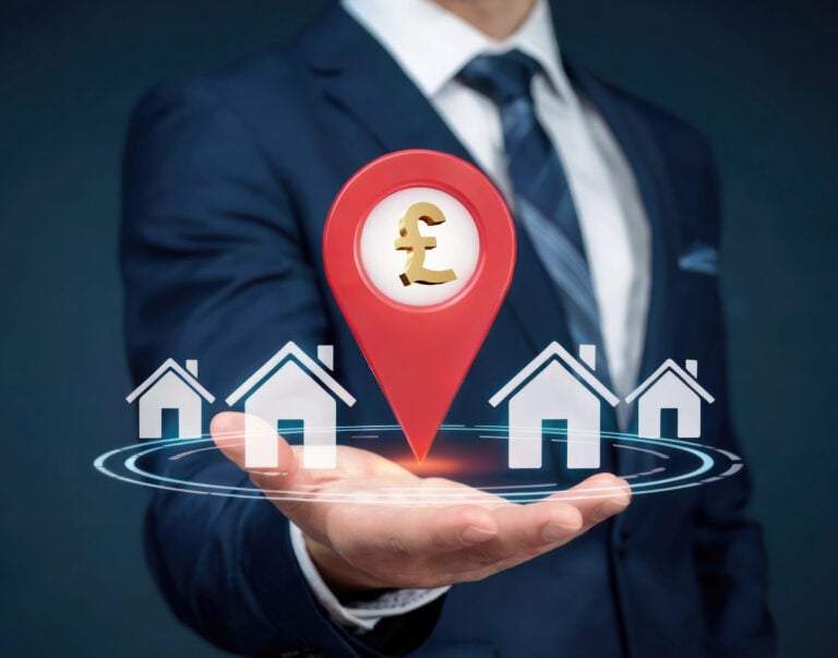 Property investment concept with pound symbol and houses in businessman’s hand