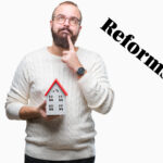 Landlord holding a model house while thinking about planning reforms
