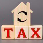 House-shaped block with tax letters symbolizing property tax reform