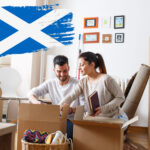 Couple unpacking boxes in new home with Scottish flag overlay