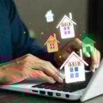 Person using laptop with digital house icons showing sold signs, symbolizing online property auctions.