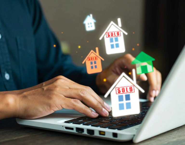 Person using laptop with digital house icons showing sold signs, symbolizing online property auctions.
