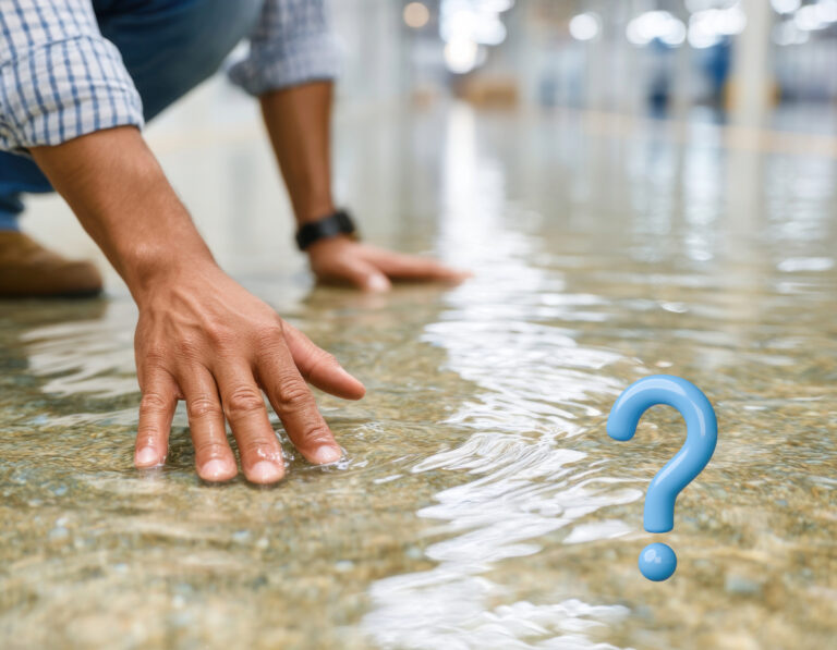 Man inspecting water damage on floor with question mark symbolizing uncertainty about repairs.