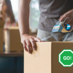 Person sealing a moving box with tape, symbolizing tenants moving out early.