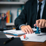 Official stamping housing licence documents on a desk, representing landlord licensing policy.