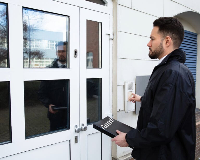 Council officer presses door buzzer while conducting a housing inspection visit.
