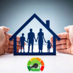Hands shielding a paper-cut family inside a house with an energy efficiency gauge below.