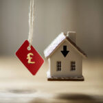 Small house model with pound sign tag symbolising UK house price decline.