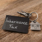 House key with tag labeled “Inheritance Tax” symbolizing property tax concerns for homeowners