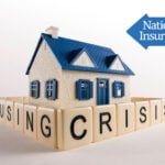 Model house surrounded by “housing crisis” blocks with National Insurance sign.