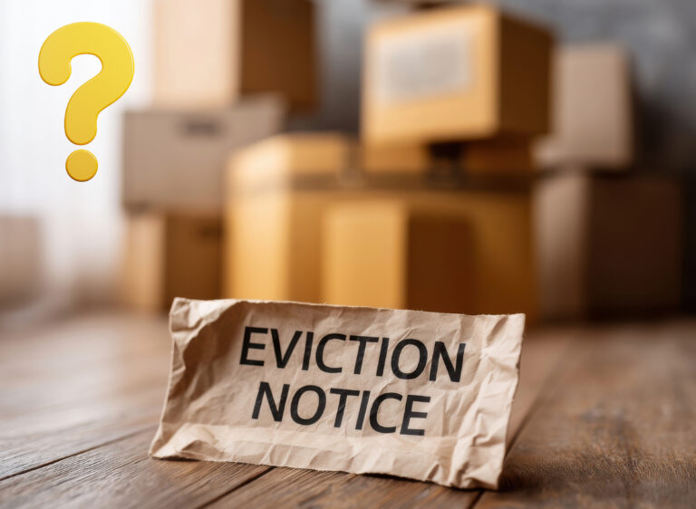 Crumpled eviction notice with moving boxes in the background, symbolizing housing uncertainty.