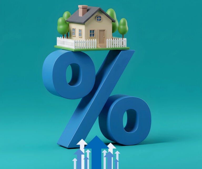 Small house balanced on a large blue percent symbol representing rising UK mortgage rates