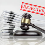 Gavel beside rejected legal documents representing government refusal to review County Court system