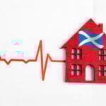 Red house with Scottish flag beside a heartbeat line symbolising Scotland’s housing market health