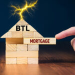 Hand pulling a wooden block labeled “Mortgage” from a house marked “BTL”, symbolizing buy to let lending and finance changes.