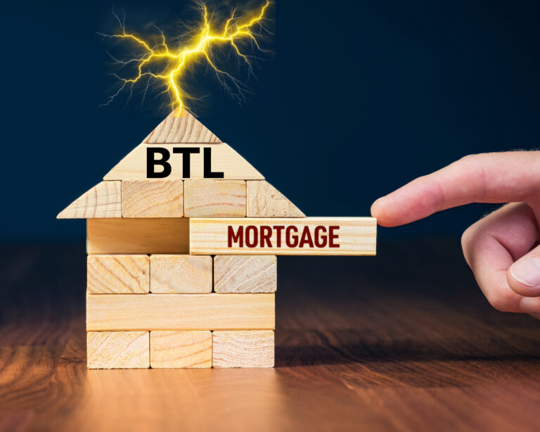 Hand pulling a wooden block labeled “Mortgage” from a house marked “BTL”, symbolizing buy to let lending and finance changes.